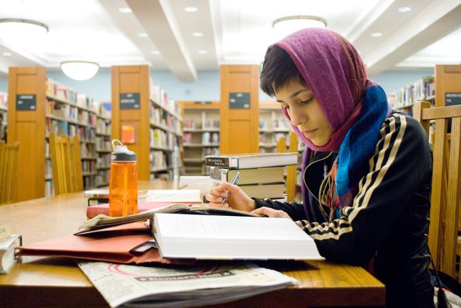 A person studying at a table with open books in a library