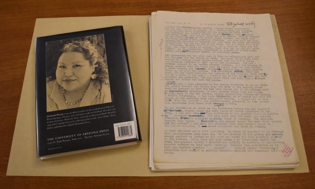 A manilla folder open, on the right there is a stack of papers, on the left there is a book with the back cover showing the author's photograph.