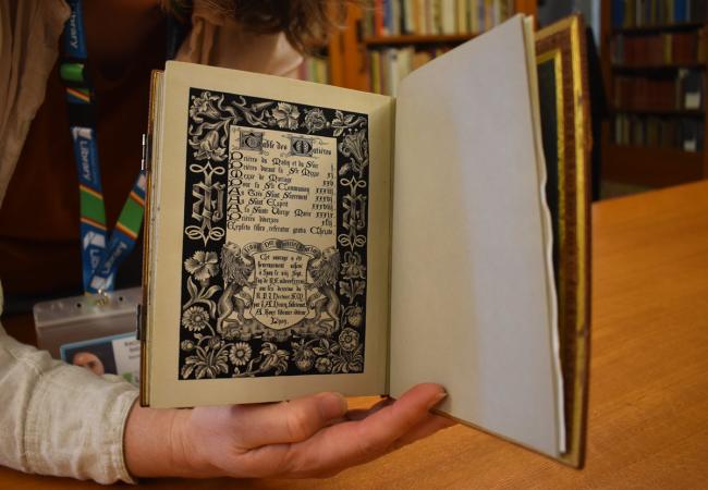 A person inside a library holding a book open, the pages are made of silk.